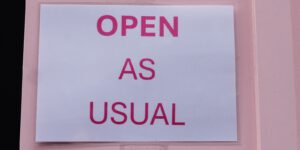 A sign on a door that says open as usual