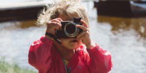 selective focus photography of girl using a camera